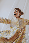 Enfant portant la robe ALMA coupe longue à manches longues boutonnée sur le devant couleur beige motif fleurs jaunes en coton bio certifié GOTS style vintage