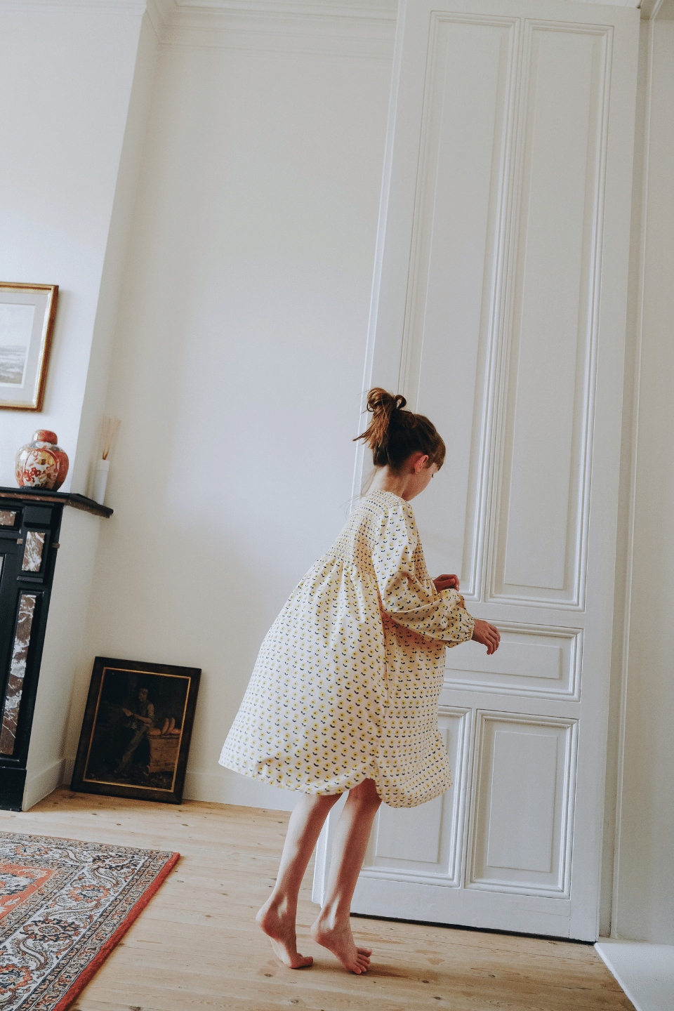 Enfant portant la robe ALMA coupe longue à manches longues boutonnée sur le devant couleur beige motif fleurs jaunes en coton bio certifié GOTS style vintage