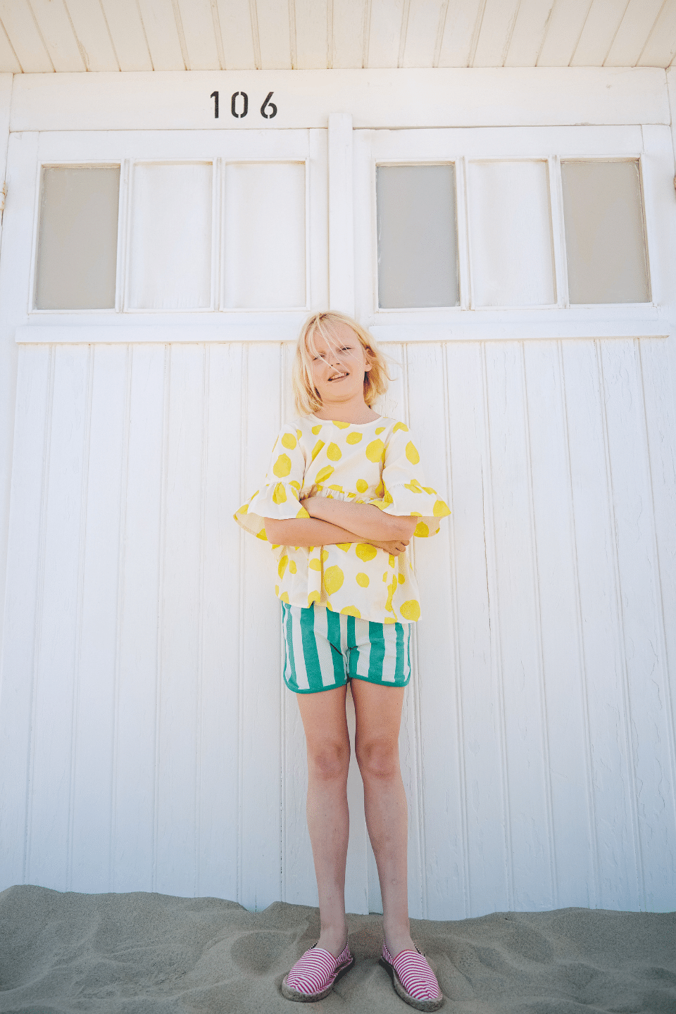 Fille portant la blouse PIA motif citron et le short KIM à rayures vertes à la plage, en coton bio style vintage mixte unisexe
