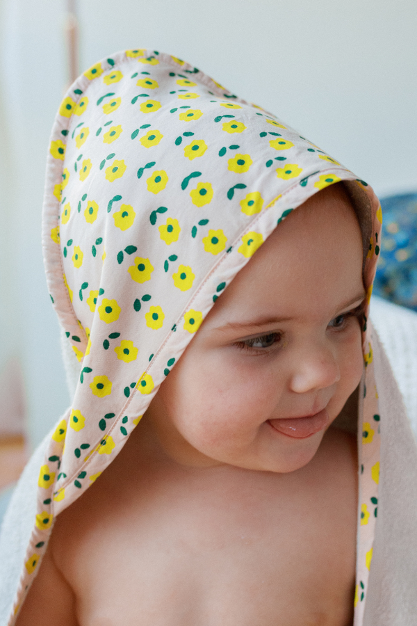 Bébé sortant du bain avec la cape de bain en coton bio de la capsule bébé naissance Baby Care motif fleur
