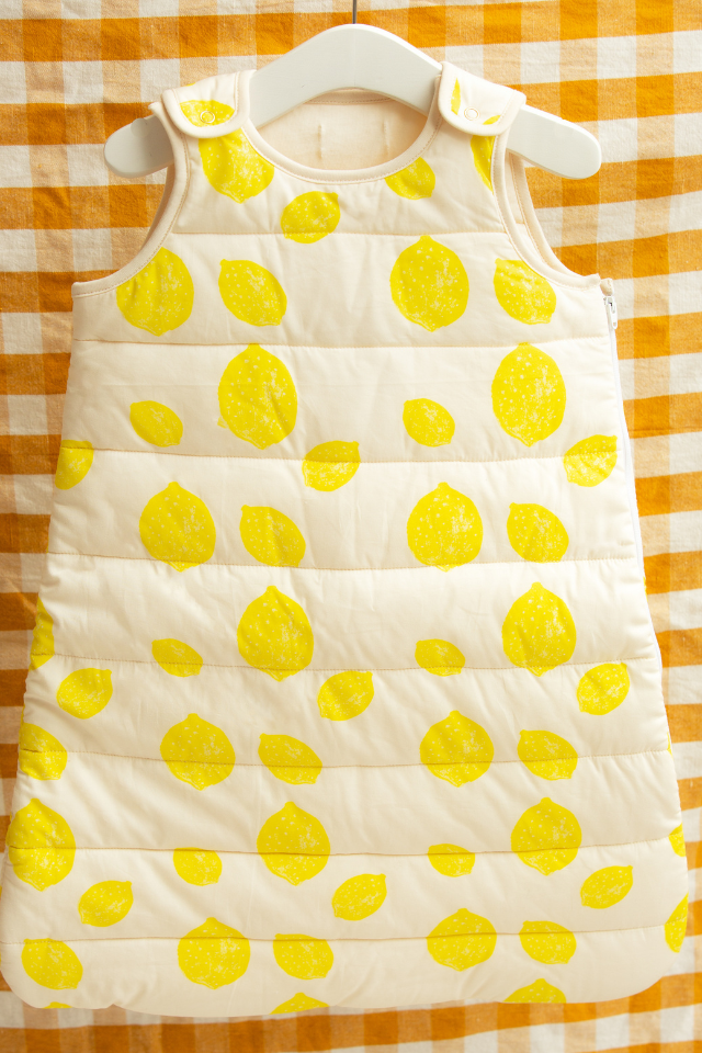 Gigoteuse au motif Lemon de la capsule bébé naissance en coton bio Baby Care suspendue par un ceintre.